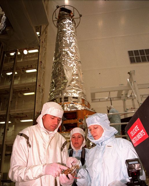 In the Vertical Processing Facility, STS-93 Pilot Jeffrey S. Ashby, Mission Specialist Catherine G. Coleman and Commander Eileen M. Collins look at a hinge used on the solar panels of the Chandra X-ray Observatory. Members of the STS-93 crew are at KSC for payload familiarization, including Mission Specialist Michel Tognini of France, representing the Centre National d'Etudes Spatiales (CNES). Collins is the first woman to serve as a shuttle mission commander. She was the first woman pilot of a Space Shuttle, on mission STS-63, and also served as pilot on mission STS-84. The fifth member of the crew is Mission Specialist Steven A. Hawley. Chandra is scheduled for launch July 9 aboard Space Shuttle Columbia, on mission STS-93 . Formerly called the Advanced X-ray Astrophysics Facility, Chandra comprises three major elements: the spacecraft, the science instrument module (SIM), and the world's most powerful X-ray telescope. Chandra will allow scientists from around the world to see previously invisible black holes and high-temperature gas clouds, giving the observatory the potential to rewrite the books on the structure and evolution of our universe