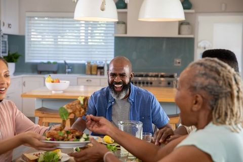 Smiling Multigenerational Family Enjoying Meal Together in Modern Kitchen