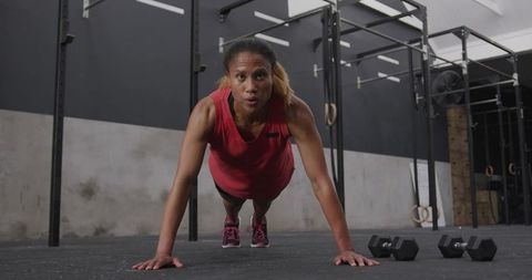 Focused female athlete performing push-ups in modern gym