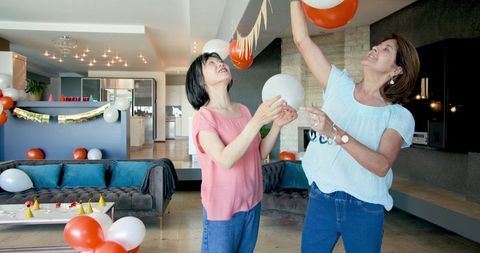 Senior friends organizing birthday party decor in modern living room