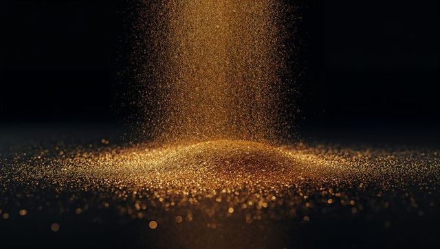 Falling golden glitter forming shimmering mound with warm glow and bokeh sparkle
