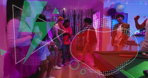 Young adults dancing at neon house party with pool table and metallic fringe backdrop