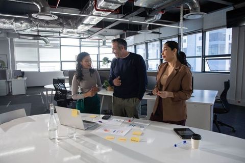 Diverse team collaborating at meeting table in modern open-plan office reviewing charts