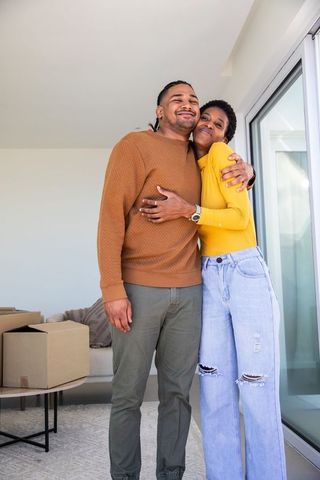 Joyful Couple Embracing in New Apartment with Moving Boxes