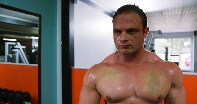 Muscular man sweating in a gym after an intense workout, showcasing strength and dedication. Useful for fitness promotions, workout programs, gym advertisements, and health and wellness articles.