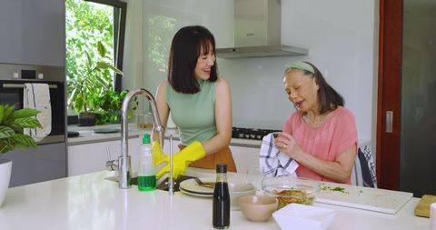 Asian family bonding in modern kitchen washing dishes together