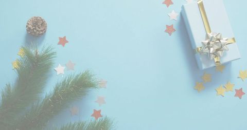 Pastel Holiday Gift Featuring Gold Ribbon, Silver Bow, Evergreen Sprig, Star Confetti on Pale Blue