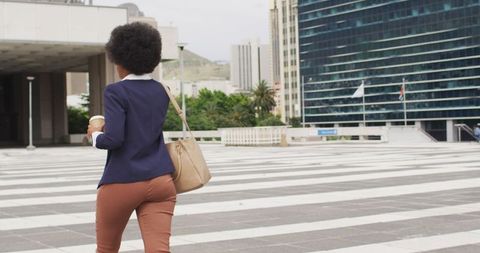 Businesswoman Walking in Urban Setting with Coffee and Smartphone
