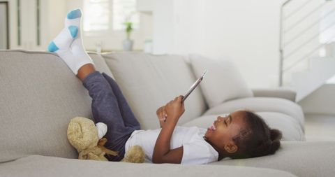 Laughing Child Using Tablet on Sofa at Home - Download Free Stock Images Pikwizard.com