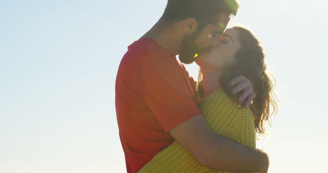 Captured moment of romantic couple kissing outdoors on a bright, sunny day. Use for themes of love, romance, relationships, affection, and happiness in advertising, social media, and lifestyle content.