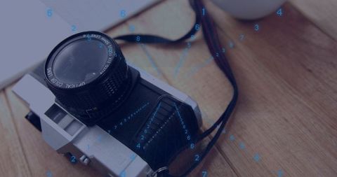 Vintage slr camera resting on wooden table with film lens and retro notebook closeup
