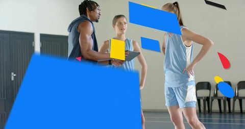 Basketball coach guiding female players with tablet during tactical timeout on indoor court