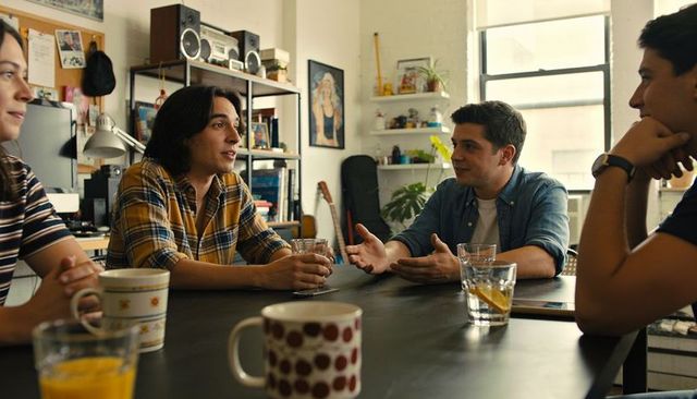 Friends leaning around table sharing ideas in bright apartment living room casual hangout