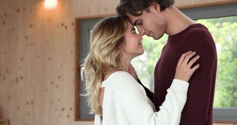 Romantic couple embracing in cozy cabin with large window