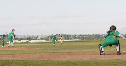 Female softball players practicing outdoors, emphasizing teamwork