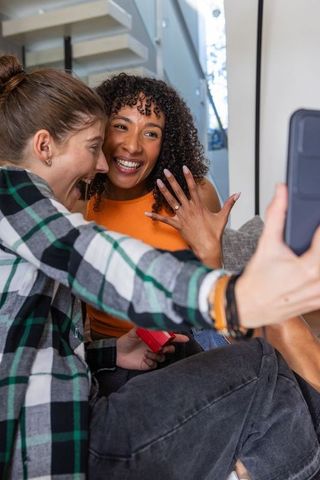 Celebration and engaged couple taking selfie in modern living room