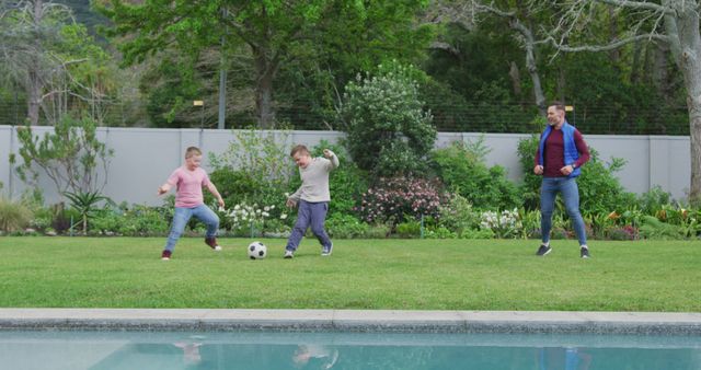 Father enjoys time with sons playing soccer in a lush backyard garden beside a swimming pool. Ideal for concepts around family bonding, outdoor activities, and healthy living. It shows family values, parenting, and the joy of spending time outdoors in a beautiful garden setting.