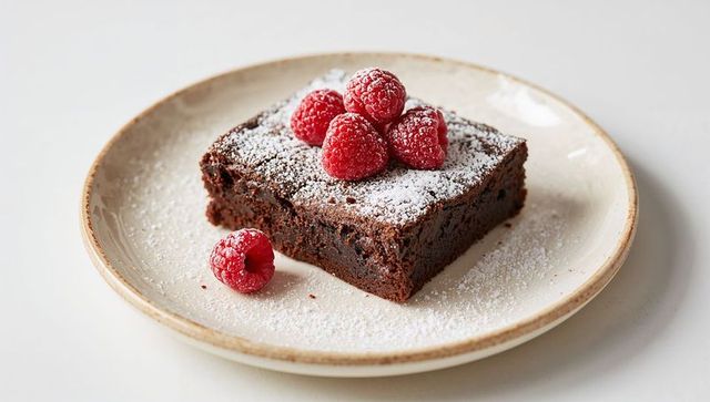 Decadent Chocolate Brownie Topped with Raspberries and Powdered Sugar on Ceramic Plate