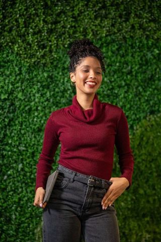 Confident african american woman holding tablet, smiling against vibrant green living wall