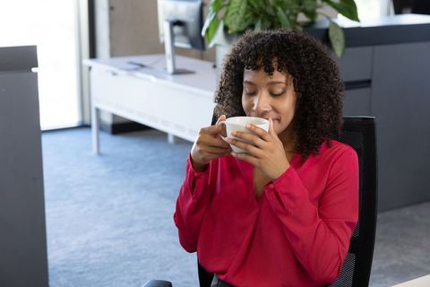 Woman enjoying warm taste of office coffee break