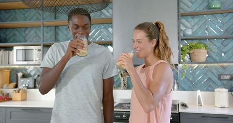 Diverse Couple Enjoying Fresh Juice Together in Modern Kitchen Setting