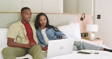 Couple Relaxing with Laptop on Bed in Modern Bedroom