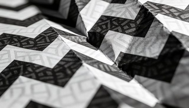 Monochrome crumpled chevron paper texture showing sharp folds, creases and zigzag pattern
