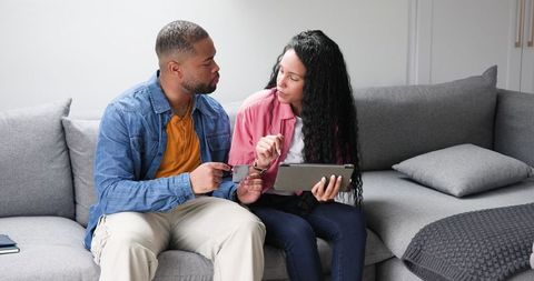 Couple Planning Holiday with Tablet and Documents at Home