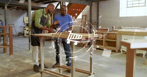 Carpenter mentoring apprentice measuring wooden frame and planning furniture in workshop