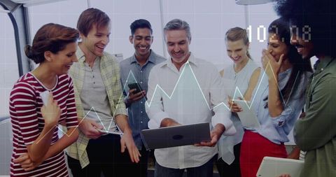 Senior leader presenting data to diverse team using laptop, tablet and smartphones