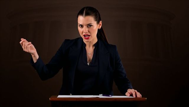 Confident female presenter delivering passionate speech from lectern, gesturing for emphasis