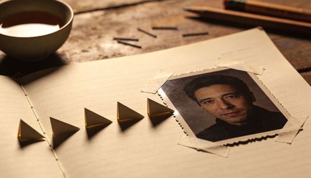 Taped portrait resting on lined notebook with gold origami triangles and cup
