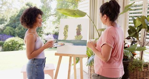 Women Engaging in Joyful Outdoor Painting Activity