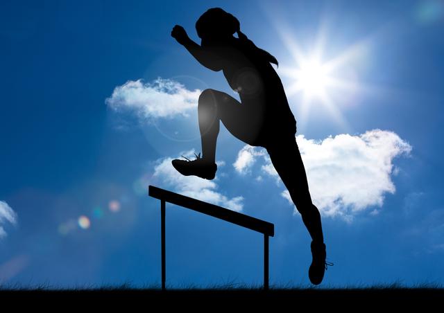 Silhouette of a female athlete jumping over a hurdle with a bright sunny sky and clouds in the background. This can be used for illustrating concepts such as athleticism, training, determination, energy, and outdoor sports activities. Perfect for sports advertisements, motivational posters, and fitness-related articles.