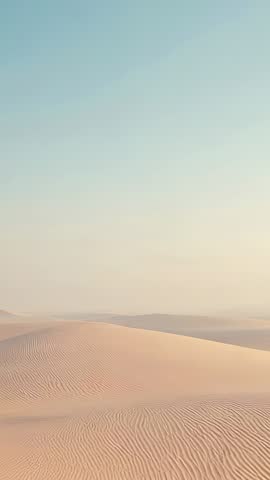 Vertical desert dune panning revealing wind-sculpted sand ripples and pale sky