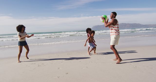 African american parents and their children playing with a ball on the beach. family outdoor leisure time by the sea.