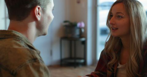 Young Couple Engaging in Lively Conversation at Coffee Shop