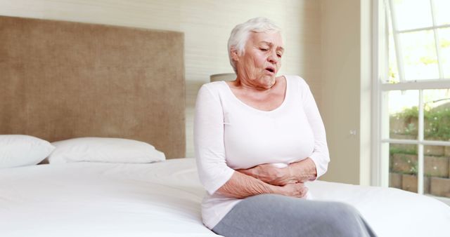 Elderly Woman Experiencing Stomach Pain Sitting on Bed - Download Free Stock Images Pikwizard.com