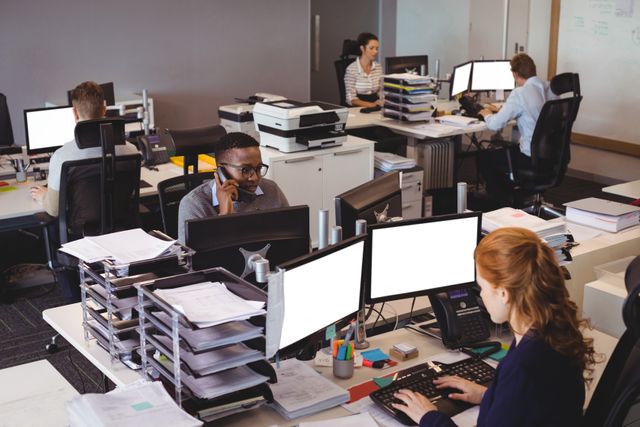 Diverse team of business professionals working at desks in a modern office. Employees are using computers, phones, and office supplies, indicating a productive and collaborative environment. Ideal for illustrating corporate culture, teamwork, and modern office settings in business presentations, websites, and marketing materials.