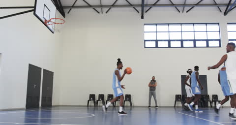 Basketball Team Practicing with Coach Observing Progress