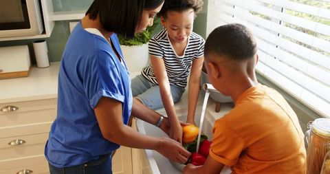 Family bonding in kitchen washing colorful bell peppers together