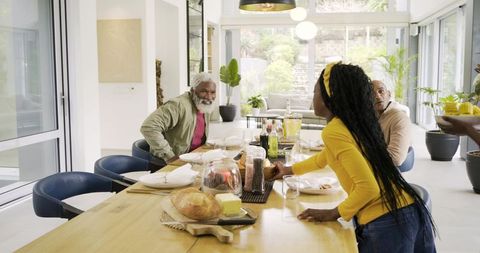 Multigenerational Black Family Sharing Bread at Bright Modern Dining Table