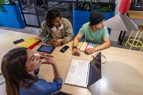 Young diverse team collaborating around laptop in modern coworking space