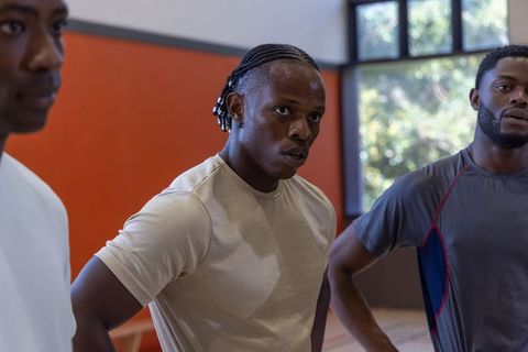 African american men pausing during intense basketball training on indoor hardwood court