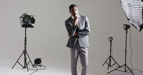 Man in grey suit posing with studio lighting equipment