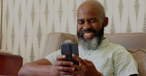 Relaxed Man Using Smartphone and Staying Hydrated at Home