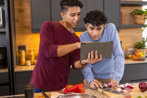 Two Young Men Bonding Over Digital Cookbook in Modern Kitchen