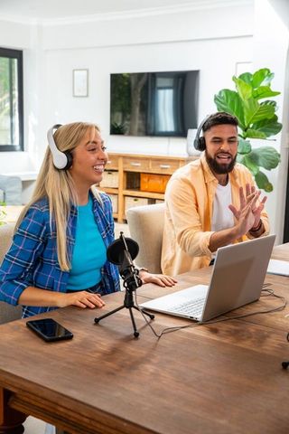 Happy Team Collaborating on Podcast with Laptop and Microphones