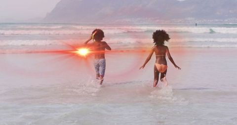 Joyful Siblings Splashing in Ocean Waves at Sunset