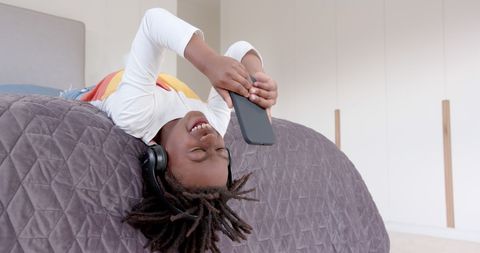 Joyful Boy Using Smartphone Wearing Headphones at Home